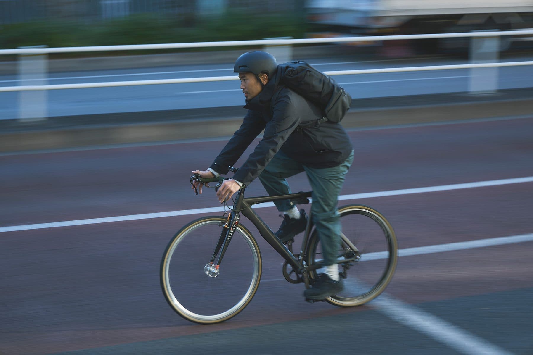 黒いバックパックを背負って街の道路を自転車で走る人