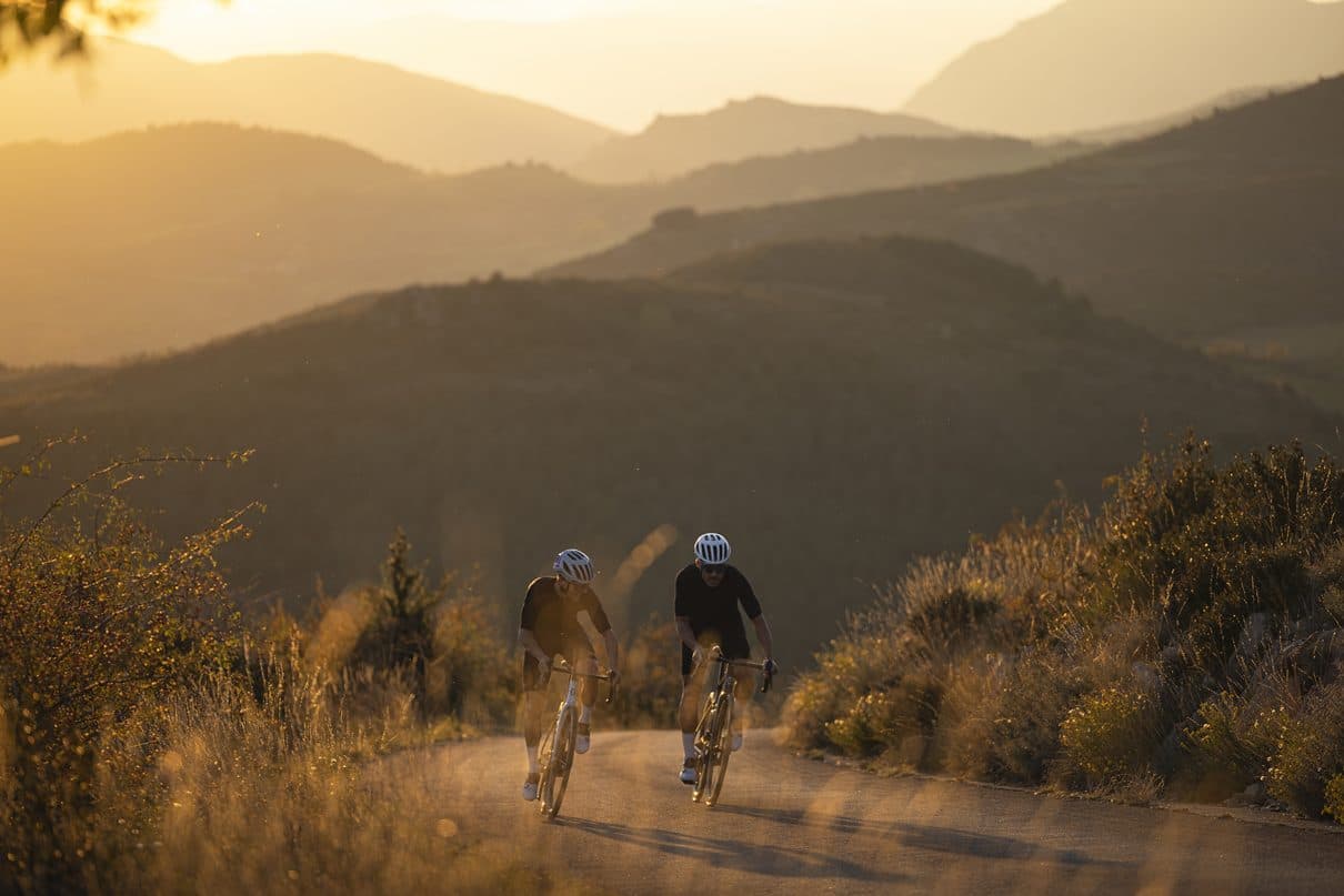 夕日の山道を登ってくる2人のロードバイク